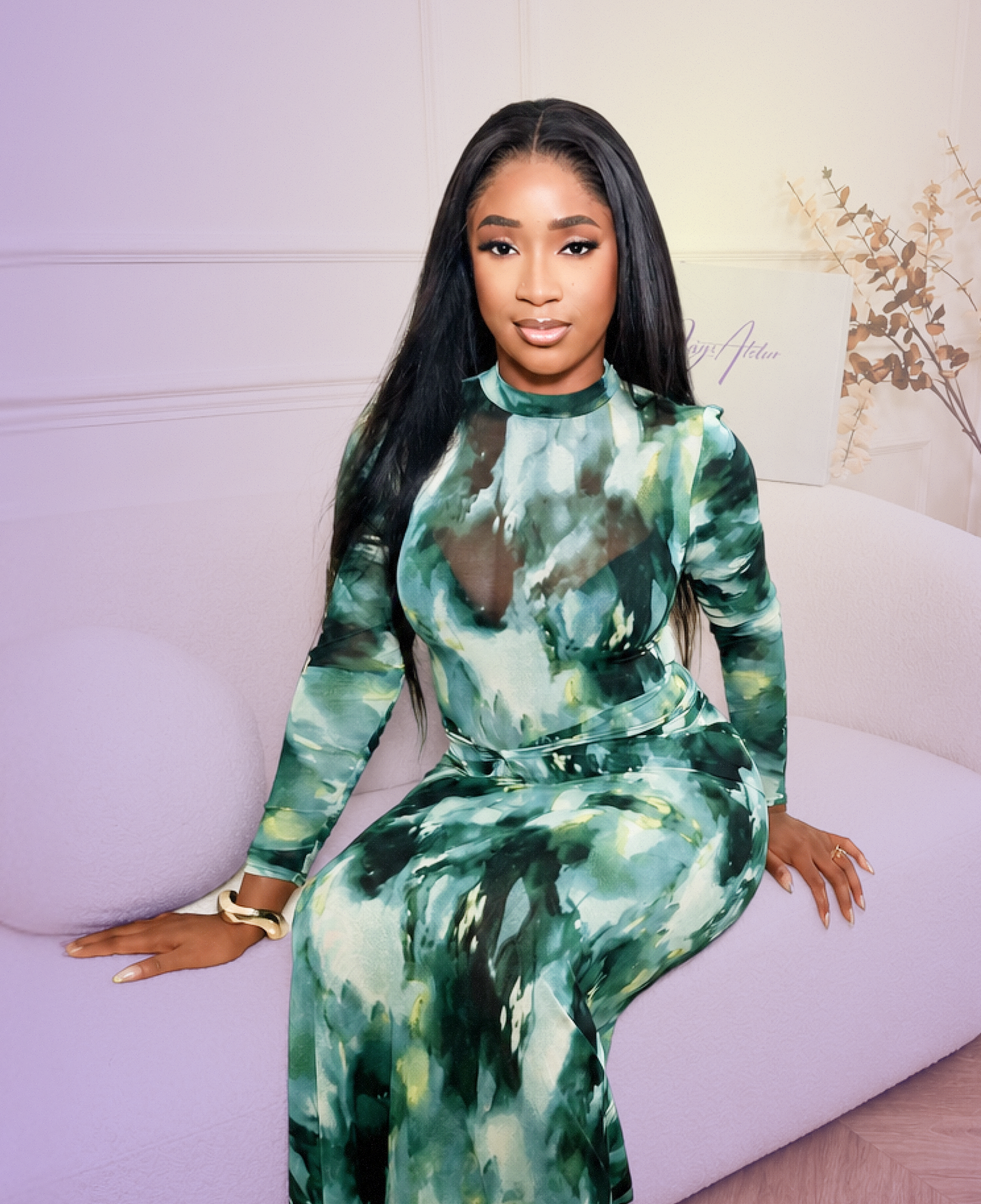 Woman in a green tie-dye outfit sitting on a white couch.